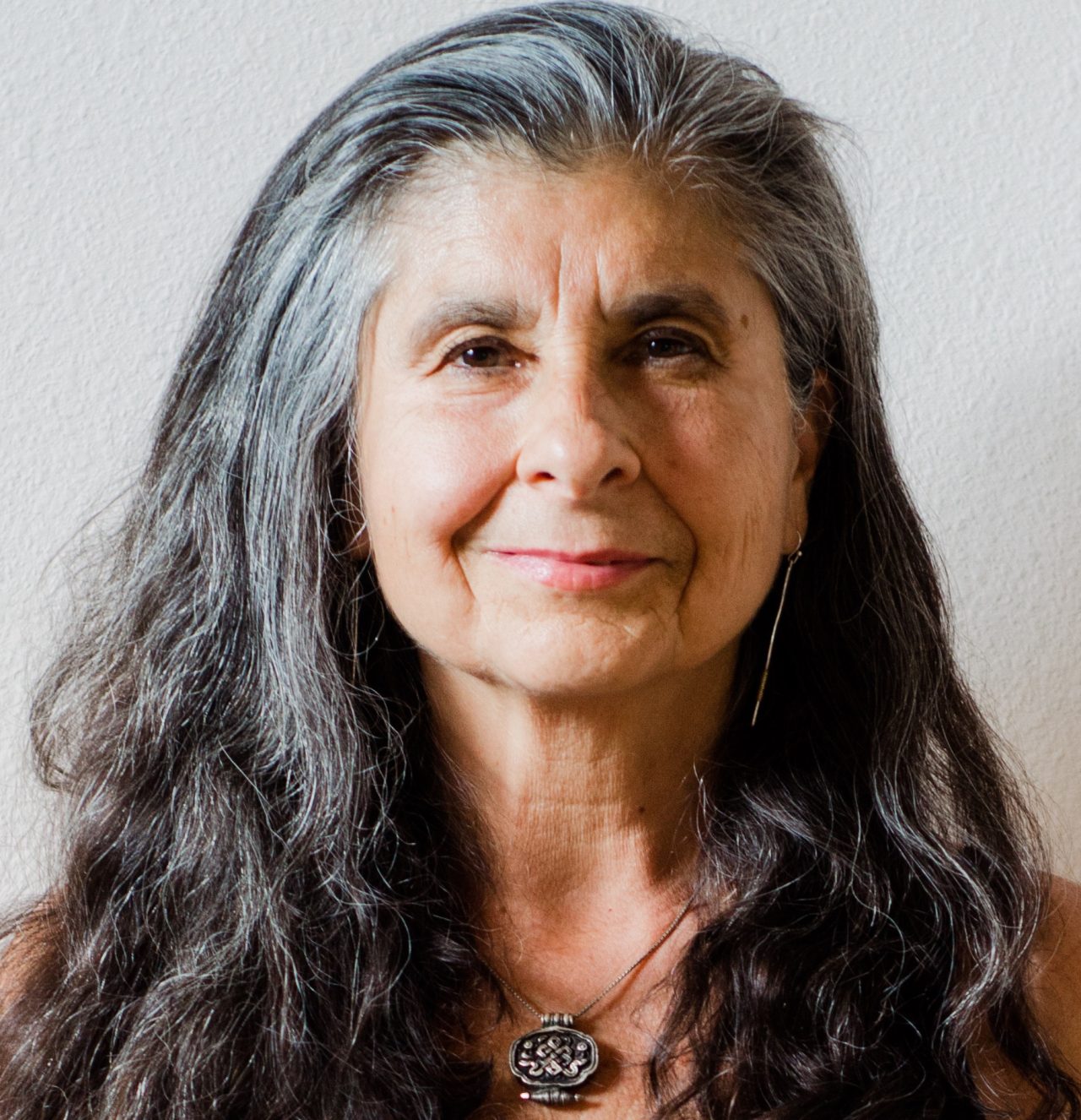 Op de afbeelding is de auteur van 'Embodied spiritualiteit' te zien, Susan Aposhyan. Ze is een vrouw van middelbare leeftijd en heeft lang haar tot over haar schouders dat zwart/grijs is.
